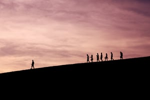 people following a man on a hill