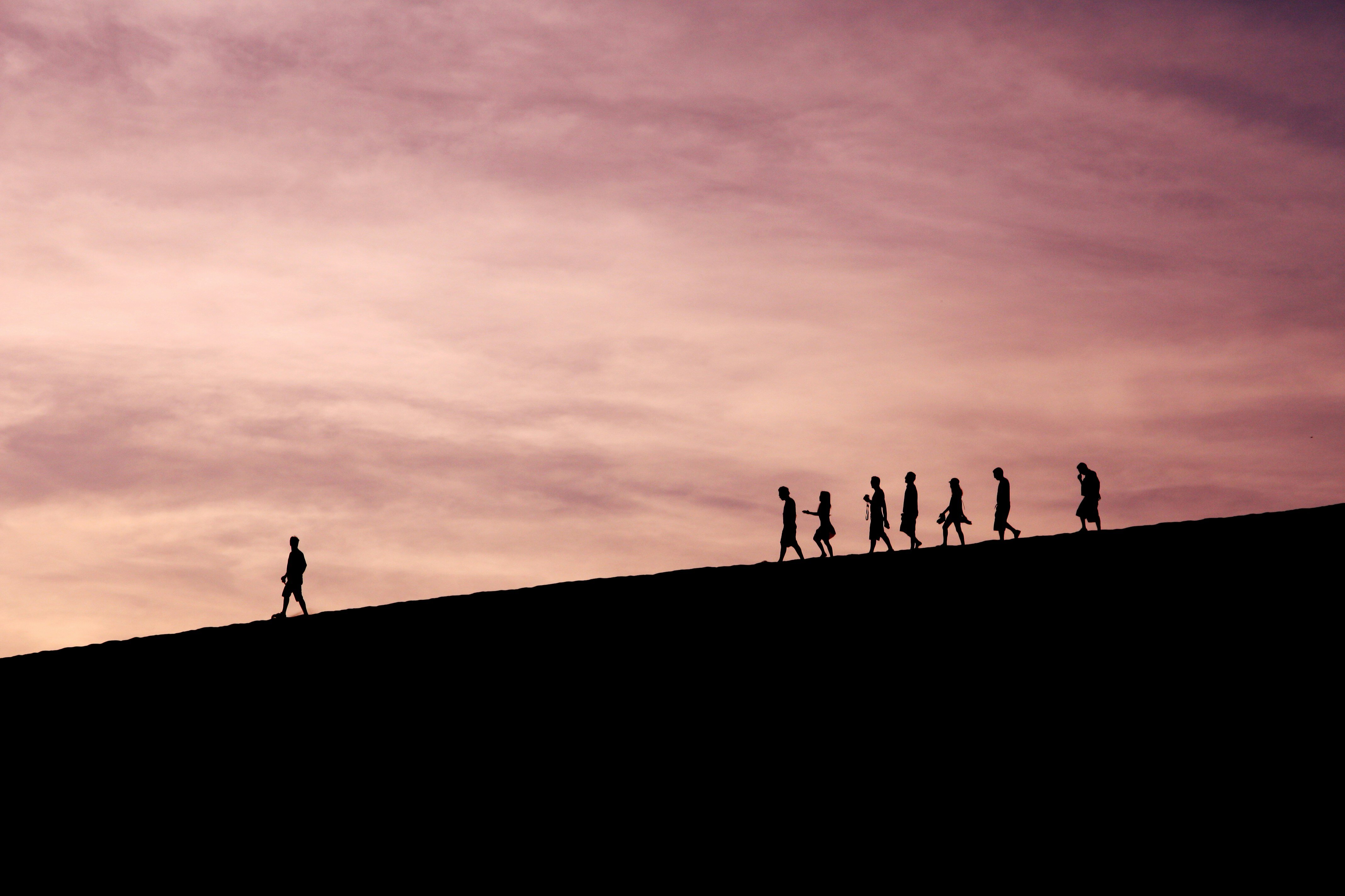 people following a man on a hill