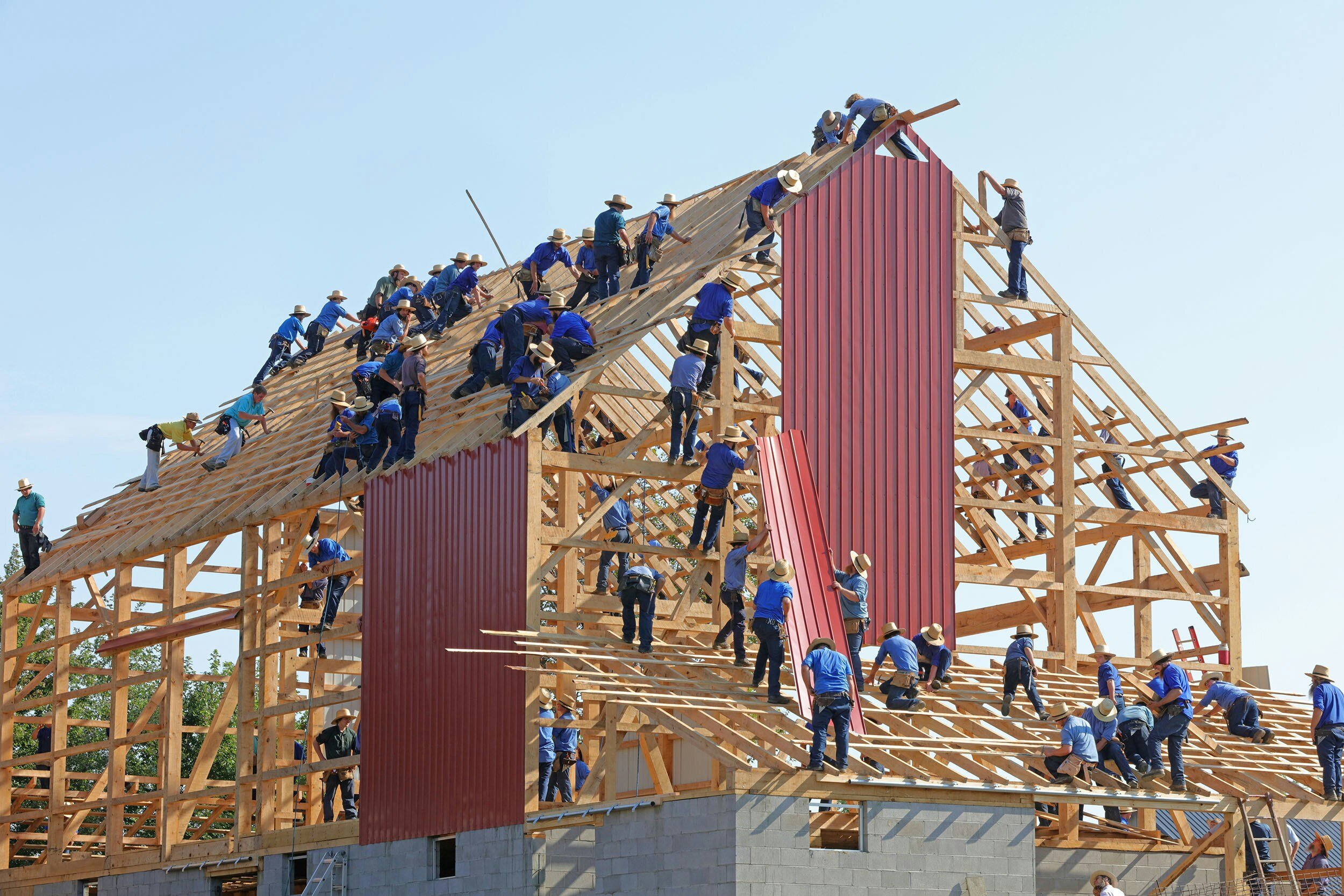 lots of people building a wooden house frame